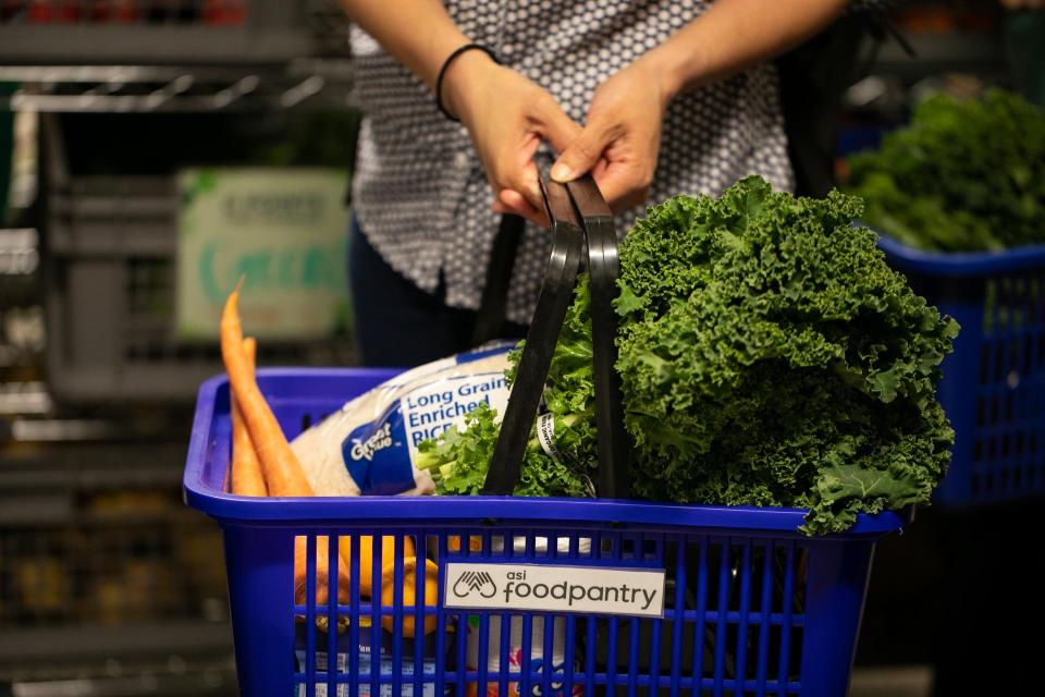 ASI Food Pantry basket filled to the brim with garden carrots, a bag of rice, and green kale.