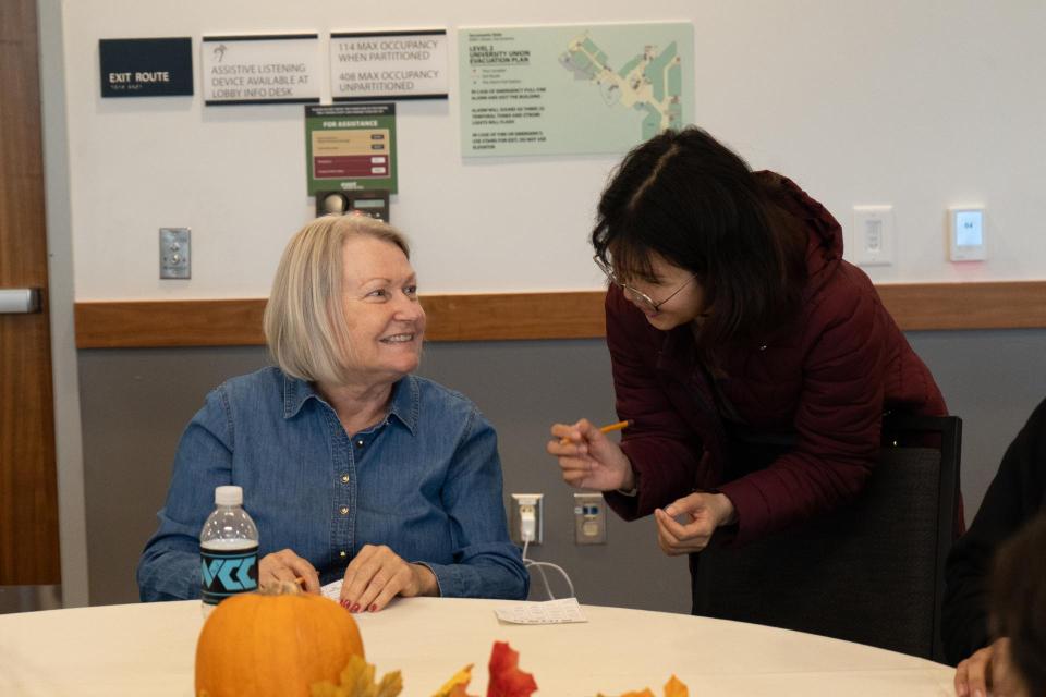 Two people at Friendsgiving Feast talking to one another at a decorated table.