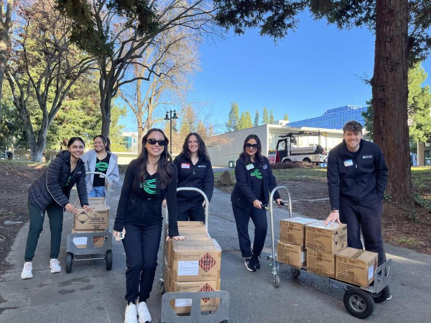 ASI Food Pantry volunteers smiling and standing next to carts with boxes of food.