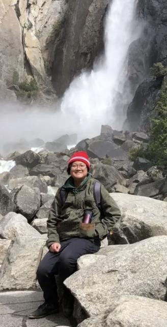 A picture of a man sitting underneath a waterfall.